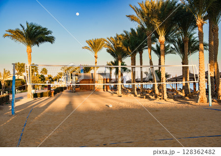 Volleyball court surrounded by palm trees and beach at sunset near tropical resort Volleyball court surrounded by palm trees and beach at sunset near tropical resort 128362482