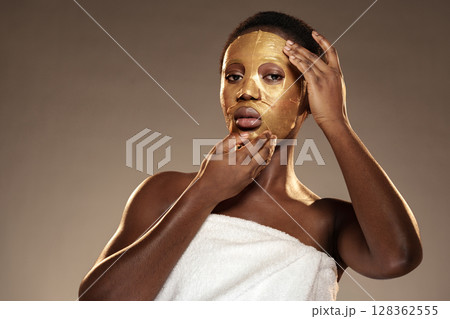 Woman applying golden facial mask in a serene indoor setting during a self-care routine for skin rejuvenation Woman applying golden facial mask in a serene indoor setting during a self-care routine for skin rejuvenation 128362555