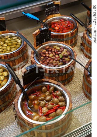 Collection of assorted olives displayed in wooden containers at a market in the afternoon 128362580