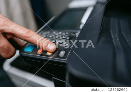 Button press on a multifunction printer for scanning documents in an office setting during daytime Button press on a multifunction printer for scanning documents in an office setting during daytime 128362662