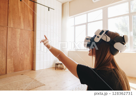 Woman experiences virtual reality in a bright indoor space during daylight hours while engaging with digital content 128362731