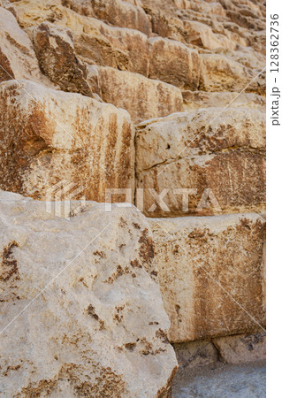 Large ancient limestone blocks form the base of a historical structure in the desert, showcasing impressive quarrying techniques used in construction 128362736