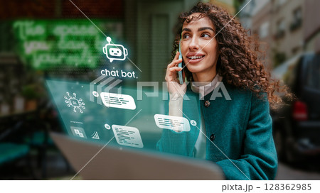 Woman engaged in conversation while using laptop in urban setting showcasing modern technology and communication tools 128362985