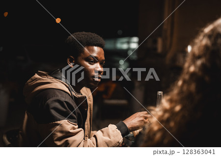 Young man engaged in a deep conversation at a night gathering outside a cafe 128363041