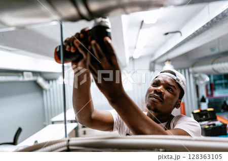 Electrician works with power tools in modern commercial building near city center after hours Electrician works with power tools in modern commercial building near city center after hours 128363105