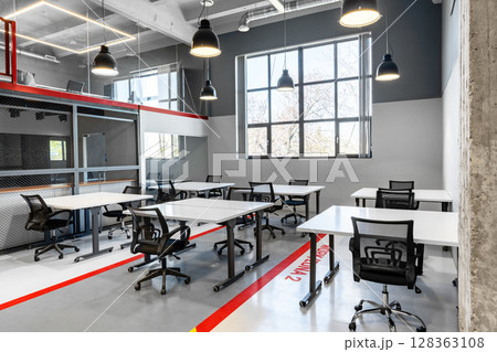 Modern coworking space featuring bright, spacious desks and ergonomic chairs in an urban setting 128363108