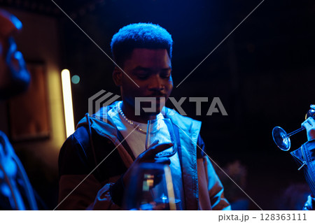 Evening gathering of friends enjoying drinks and good conversation at a lively social event in a vibrant atmosphere 128363111