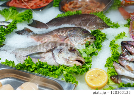 Fresh seafood on ice displayed at a market in a coastal city showcasing a variety of fish and shellfish for sale Fresh seafood on ice displayed at a market in a coastal city showcasing a variety of fish and shellfish for sale 128363123