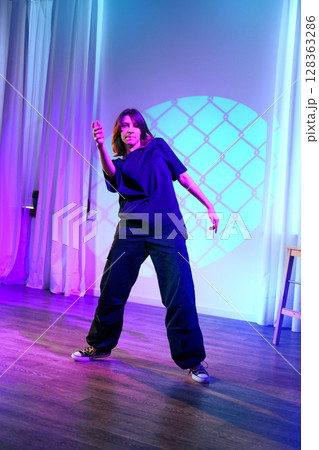 Dancer performing solo in a dimly lit studio with vibrant lighting during a contemporary dance session Dancer performing solo in a dimly lit studio with vibrant lighting during a contemporary dance session 128363286