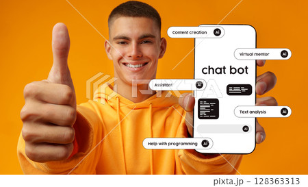Young man shows smartphone with chatbot features against a vibrant orange background while giving a thumbs up 128363313