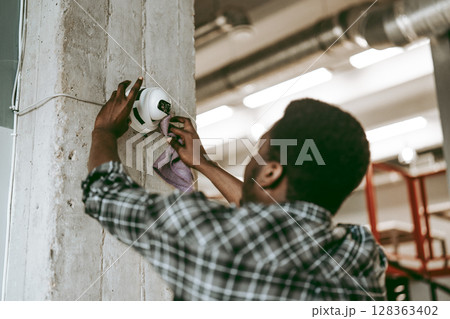 Worker cleans surveillance camera in an industrial setting during daylight hours 128363402