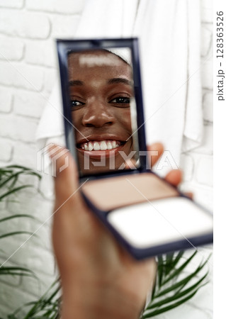 Smiling woman applying makeup in a bright bathroom with plants Smiling woman applying makeup in a bright bathroom with plants 128363526