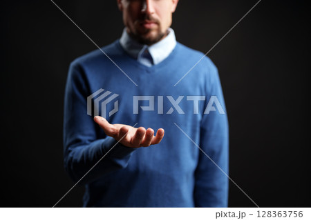 Man reaching out with open hand in a dark setting, conveying invitation or request for assistance Man reaching out with open hand in a dark setting, conveying invitation or request for assistance 128363756