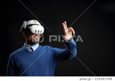 Person engaged in virtual reality experience while using motion controls indoors Person engaged in virtual reality experience while using motion controls indoors 128363766