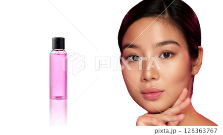Woman showcasing a beauty product with pink liquid, emphasizing skincare and wellness routine 128363767