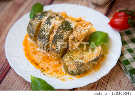 Zucchini pieces in a hot sauce on a white plate Zucchini pieces in a hot sauce on a white plate 128366042