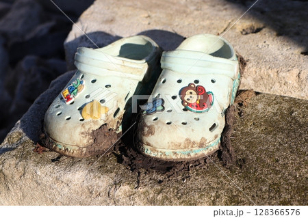 Abandoned Childs Colorful Crocs Left Behind by the Beautiful Shoreline of the Beach Abandoned Childs Colorful Crocs Left Behind by the Beautiful Shoreline of the Beach 128366576