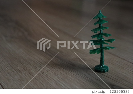 A Miniature Green Pine Tree Placed on a Wooden Floor, Perfect for Indoor Decoration 128366585