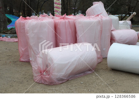 Varieties of Rolled Materials Adorned and Wrapped in Bright Pink Plastic Sheeting for Protection Varieties of Rolled Materials Adorned and Wrapped in Bright Pink Plastic Sheeting for Protection 128366586