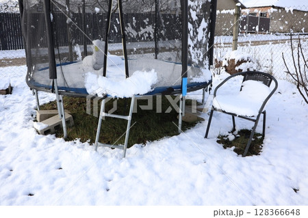 A Snow Covered Trampoline Resting in a Beautiful Winter Landscape During the Cold Season 128366648