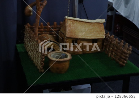 This is a traditionalstyle miniature house complete with a charming fence and a well 128366655