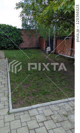 A Quiet and Serene Backyard Space Featuring Lush Green Grass and Beautiful Garden Elements 128366828