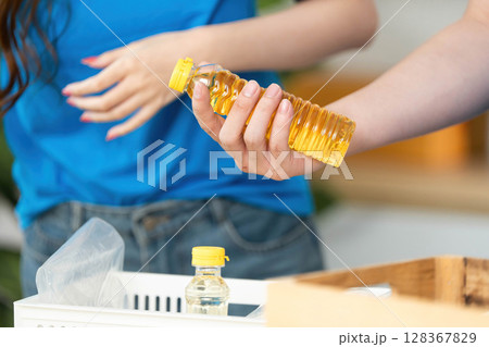 Donation and Food Sharing. Volunteer holding cooking oil for community food drive. Donation and Food Sharing. Volunteer holding cooking oil for community food drive. 128367829