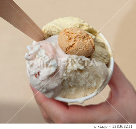 3種類のイタリアンジェラートが入ったカップを持つ手のクローズアップ 128368211