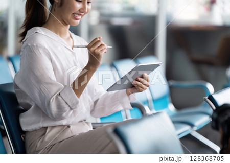 Business Professional Using Tablet at Modern Airport Terminal for Work and Communication 128368705