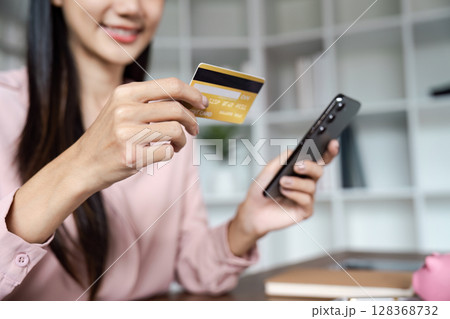 young woman is using mobile to pay for shopping online with a credit card young woman is using mobile to pay for shopping online with a credit card 128368732