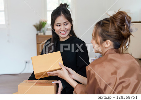 Happy Lesbian Couple Moving into New Home Unpacking Boxes and Smiling Together in Bright Modern Living Room 128368751