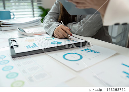 Business Meeting with Charts and Graphs on Desk, Analyzing Financial Data and Performance Metrics in a Modern Office 128368752