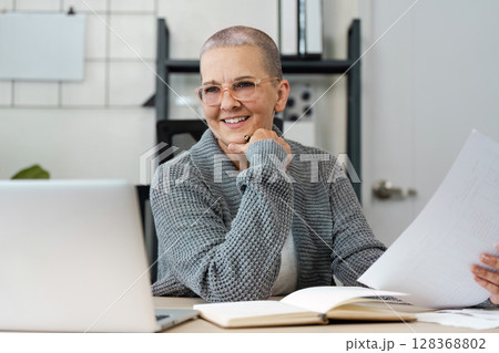 Happy Senior Woman Managing Finances and saving at Home with Laptop and Documents Happy Senior Woman Managing Finances and saving at Home with Laptop and Documents 128368802