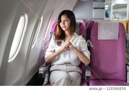 Businesswoman Relaxing in Airplane Cabin During Flight, Comfortable Travel Experience 128368850