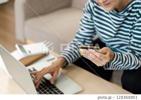 Senior woman Using Credit Card for Online Shopping on Laptop at Home Senior woman Using Credit Card for Online Shopping on Laptop at Home 128368901