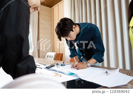 Collaborative Engineers Working on Architectural blueprint and Technical Drawings in Modern Office Setting 128369042