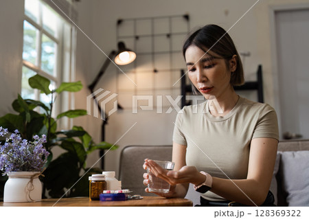 Woman Taking Medication at Home - Healthcare and Wellness Concept with Pills and Prescription Bottles Woman Taking Medication at Home - Healthcare and Wellness Concept with Pills and Prescription Bottles 128369322