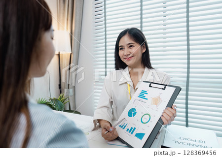Professional Business Meeting with Smiling Woman Presenting Financial Report in Modern Office Setting Professional Business Meeting with Smiling Woman Presenting Financial Report in Modern Office Setting 128369456