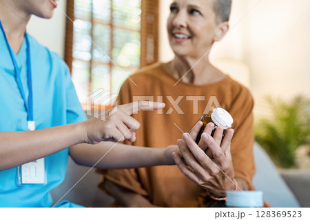 Caring Nurse Assisting Senior Woman with Medication at Home - Healthcare Home Concept 128369523