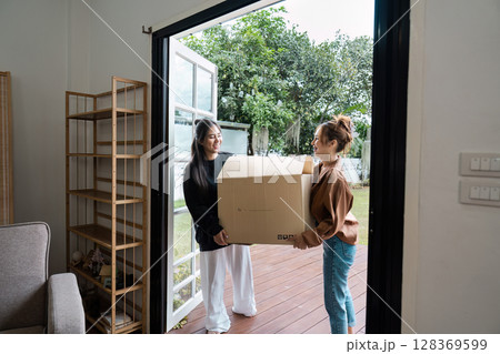 Happy Lesbian Couple Moving into New Home Together, Carrying Boxes and Smiling, Embracing New Beginnings and Fresh Start Happy Lesbian Couple Moving into New Home Together, Carrying Boxes and Smiling, Embracing New Beginnings and Fresh Start 128369599