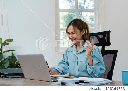 Young Professional Woman Working from Home, Smiling and Engaged in a Video Conference Call at Her Home Office Desk 128369728