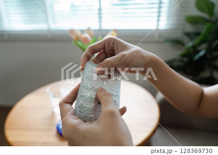 Hands Holding Medication Blister Pack in a Cozy Home Setting with Natural Light 128369730