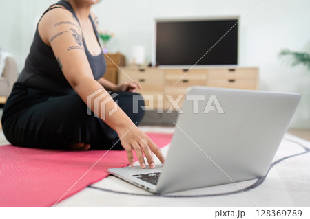 Overweight Person Engaging in Home Workout for Wellness with Laptop Guidance 128369789