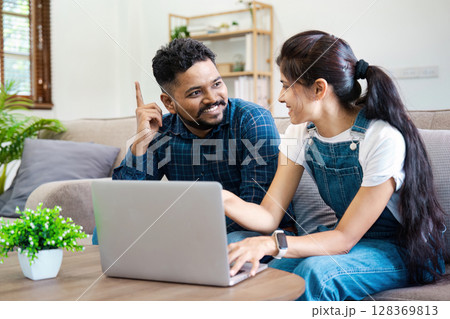 Young Indian Couple Working Together on Laptop at Home, Smiling and Discussing Ideas in a Modern Living Room Young Indian Couple Working Together on Laptop at Home, Smiling and Discussing Ideas in a Modern Living Room 128369813