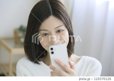 スマートフォンでメッセージを確認する女性 スマートフォンでメッセージを確認する女性 128370126