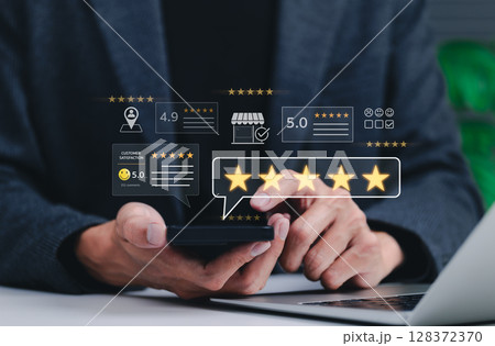 Customer review and satisfaction feedback concept. Businessman using smartphone to leave five star reviews and ratings with displaying customer satisfaction scores, comments, and service evaluations. Customer review and satisfaction feedback concept. Businessman using smartphone to leave five star reviews and ratings with displaying customer satisfaction scores, comments, and service evaluations. 128372370