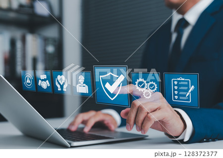 Work Safety and Compliance Concept. Businessman using laptop with icons safety, compliance, quality control, and risk management, representing workplace safety, regulations, and operational standards. Work Safety and Compliance Concept. Businessman using laptop with icons safety, compliance, quality control, and risk management, representing workplace safety, regulations, and operational standards. 128372377