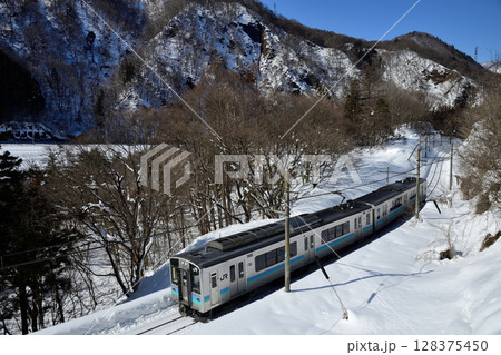 雪晴れの大糸線を走るE127系ローカル列車 128375450