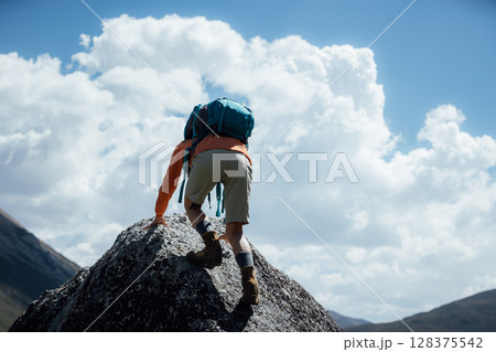 Backpacking woman climbing to high altitude mountain top Backpacking woman climbing to high altitude mountain top 128375542