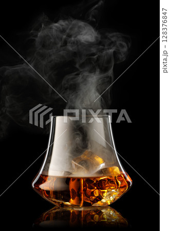 Glass of scotch whiskey with ice and cigar smoke on black background Glass of scotch whiskey with ice and cigar smoke on black background 128376847